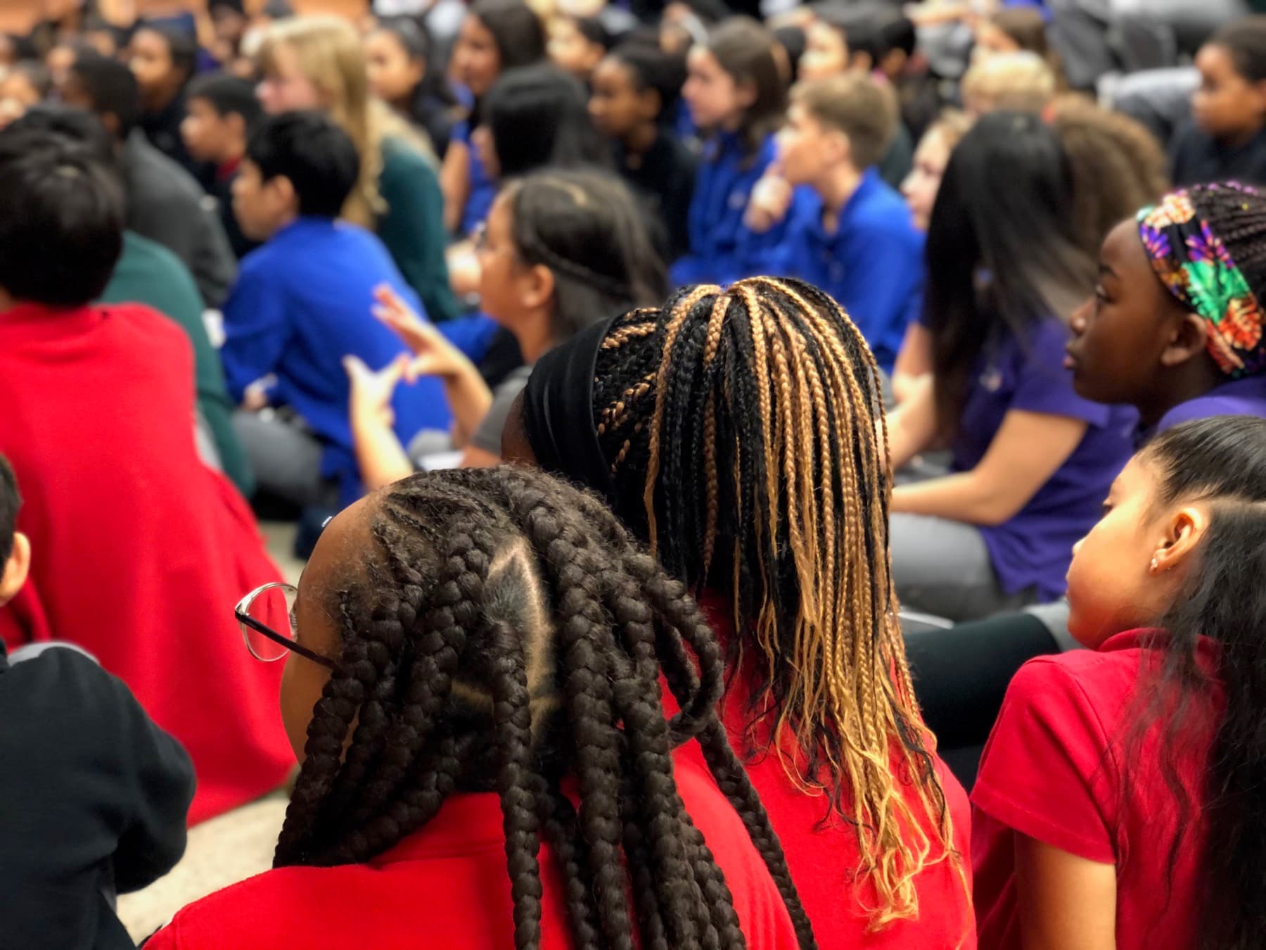 Teacher reading aloud to elementary students gathered on the classroom floor